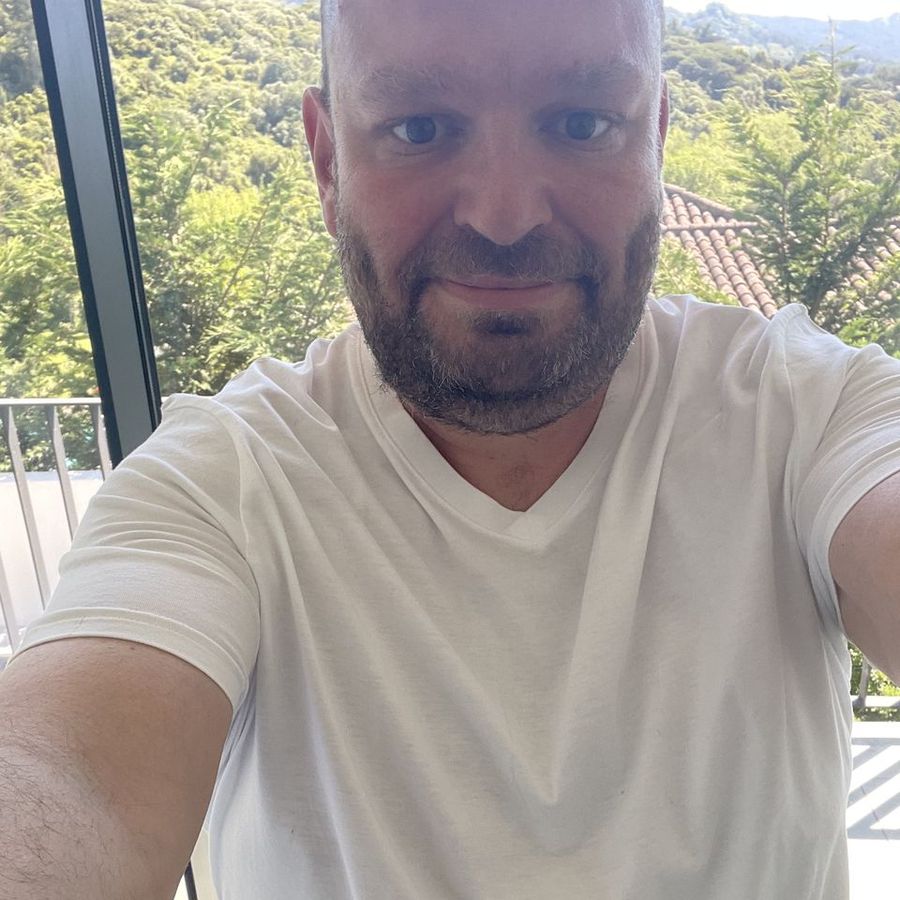 Simon Theakston on a balcony with green hills behind him